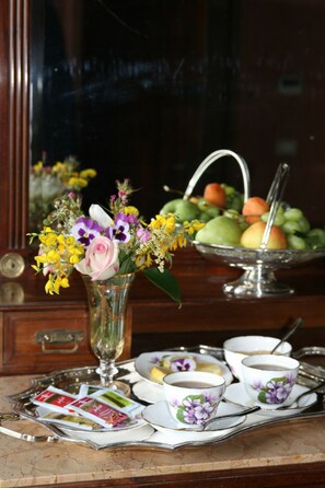 A dining table with a vase of flowers, a fruit bowl, and a tray with cups and saucers. - Galluzzo Ancient Country Villa (Casalecchio di Reno)