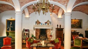 A spacious room with a fireplace, a chandelier, and a dining area with chairs and a table. - Galluzzo Ancient Country Villa (Casalecchio di Reno)