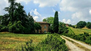 A rural landscape with a stone building, a dirt path, and lush greenery. - Galluzzo Ancient Country Villa (Casalecchio di Reno)