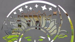 Un motif circulaire découpé, avec un visage au centre, des étoiles et un bâtiment en arrière-plan.