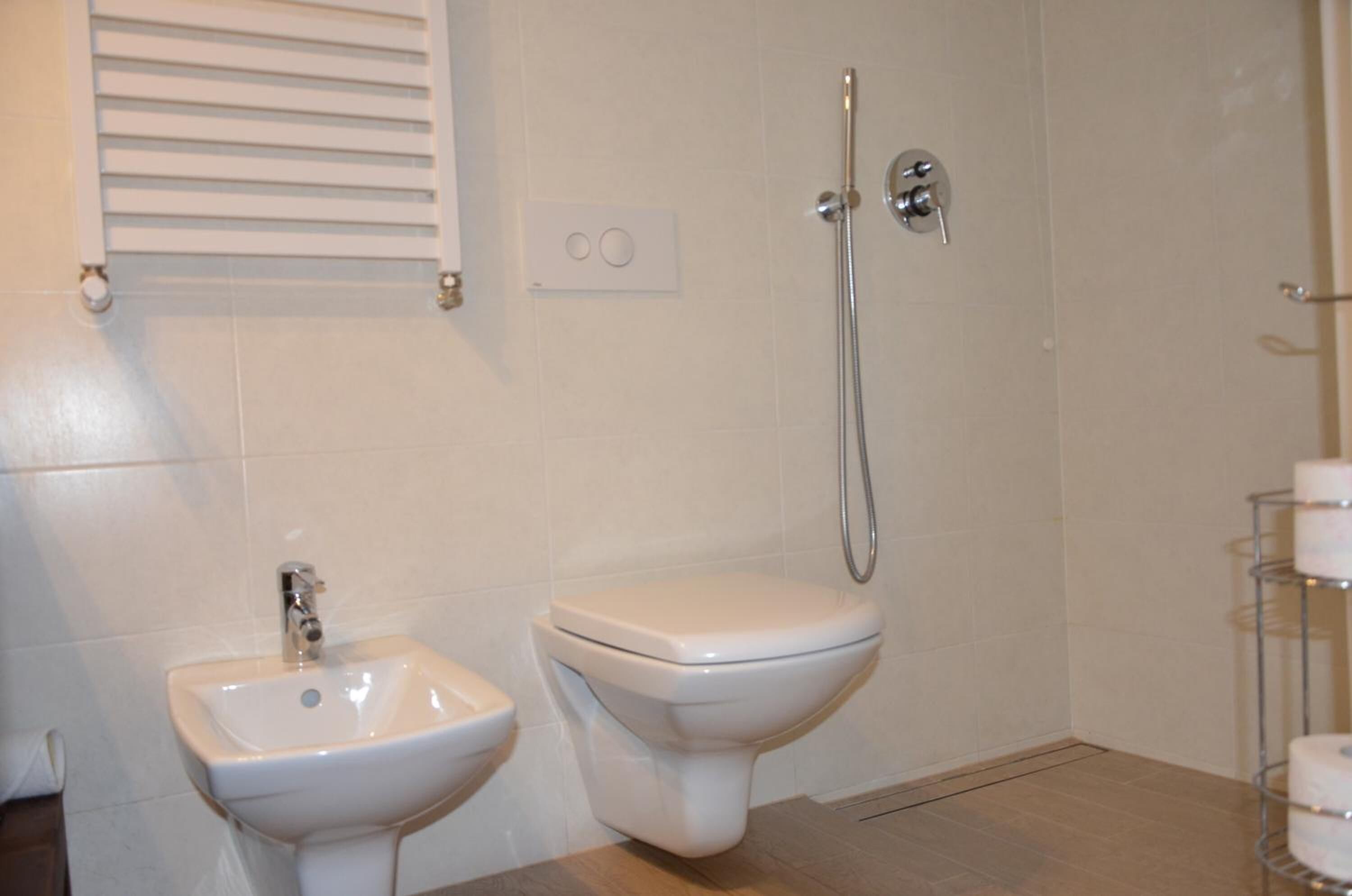A bathroom with a pedestal sink, a toilet, and a shower.