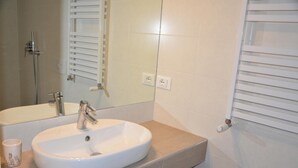 Une salle de bain avec un lavabo blanc, un miroir et un porte-serviettes.