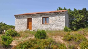 Un bâtiment en pierre avec un toit recouvert de tuiles rouges, une porte en bois et une fenêtre.
