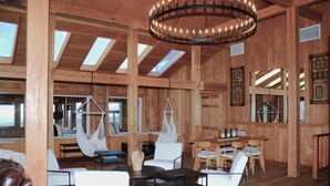 A spacious wooden interior with a high ceiling, large windows, and a central chandelier. - Bent Mountain Lodge (Copper Hill)