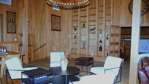 A wooden interior with a dining area, seating, and a bookshelf. - Bent Mountain Lodge (Copper Hill)