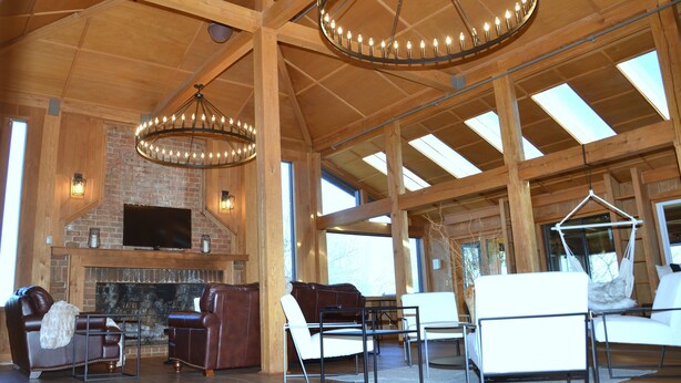 A spacious living area with a fireplace, leather sofas, and a television mounted on the wall. - Bent Mountain Lodge (Copper Hill)