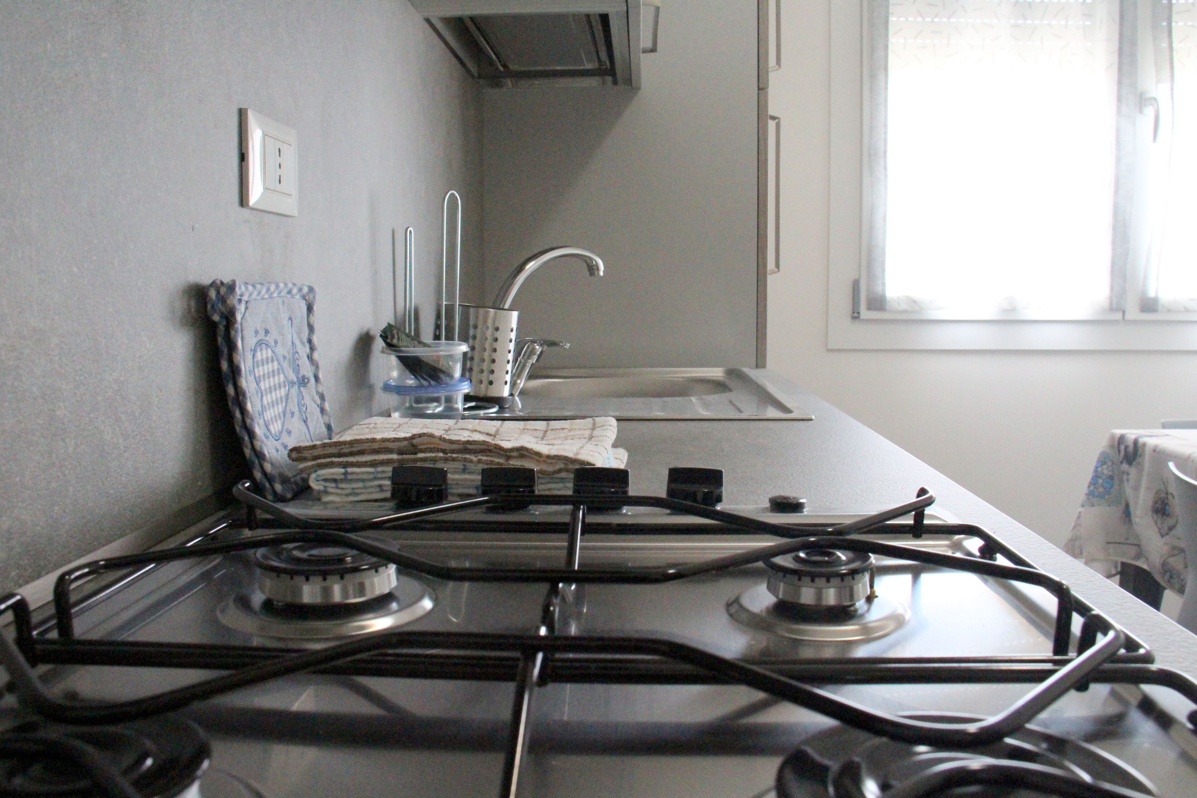 A kitchen with a gas stove, a sink, and a window.