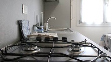 A kitchen with a gas stove, a sink, and a window.
