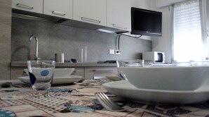 Une cuisine moderne équipée d’un téléviseur à écran plat, d’un four à micro-ondes et d’un coin repas avec une table dressée pour deux personnes.