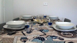 Une table à manger dressée avec des assiettes, des bols, des verres et des couverts.