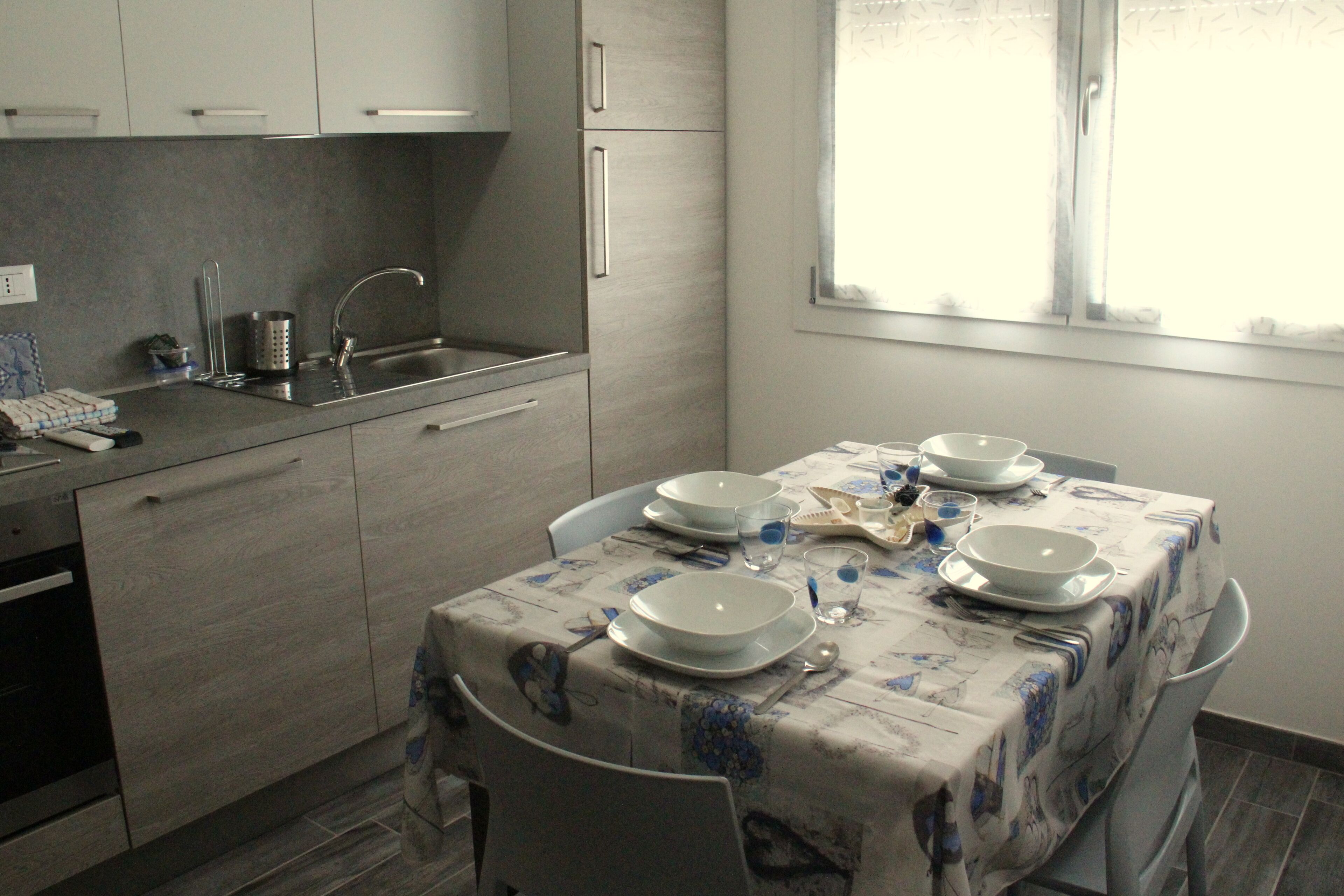 A kitchen with a dining table set for four, a sink, and cabinets.