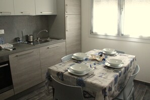 A kitchen with a dining table set for four, a sink, and cabinets. - Agriturismo La Fraterna (Porto Tolle)