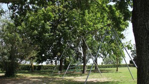Un parc avec des balançoires, des arbres et une pelouse.