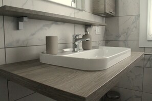A modern bathroom with a rectangular white sink, a wooden countertop, and a marble backsplash. - Agriturismo La Fraterna (Porto Tolle)