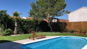 A rectangular swimming pool with a wooden deck and lounge chairs, surrounded by a well-maintained lawn and trees. - VUT Rural Dulcinea de la Mancha Pool Wifi (Fernán Caballero)