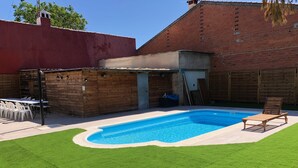 A backyard with a swimming pool, a wooden deck, and a grassy lawn. - VUT Rural Dulcinea de la Mancha Pool Wifi (Fernán Caballero)