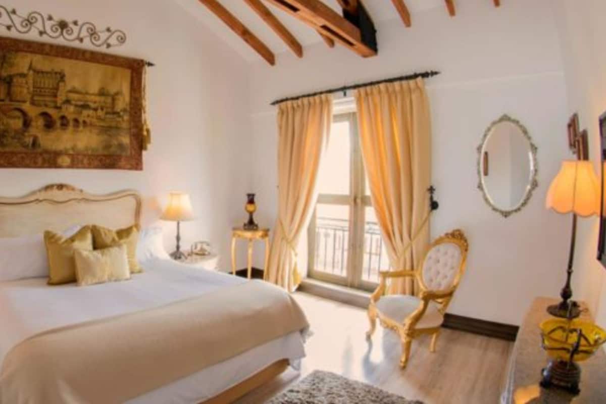 Ein Schlafzimmer mit einem großen Bett, einer Kandelaber, einem Gemälde und einem Sessel.