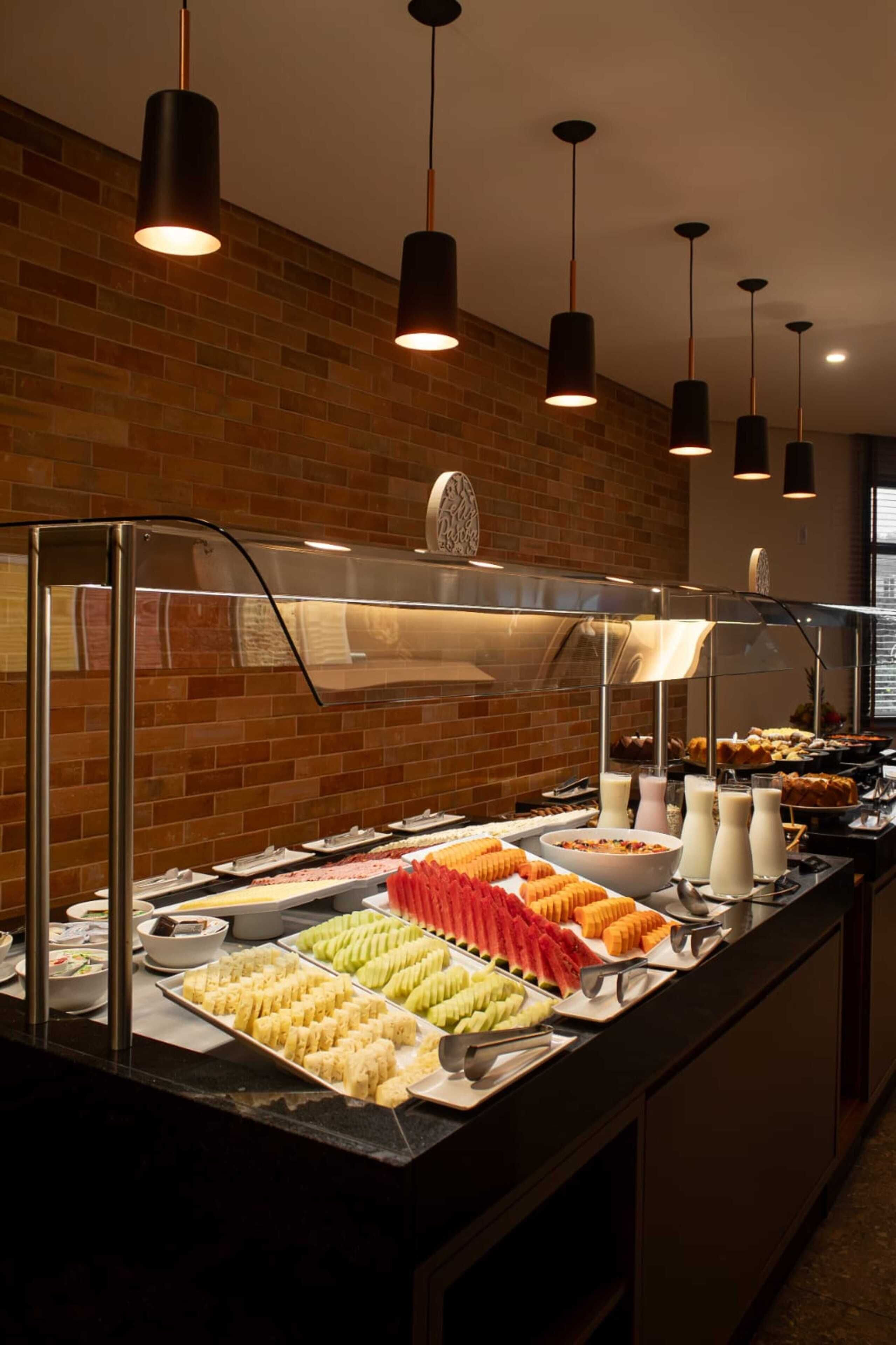 A buffet with various food items and a brick wall background.