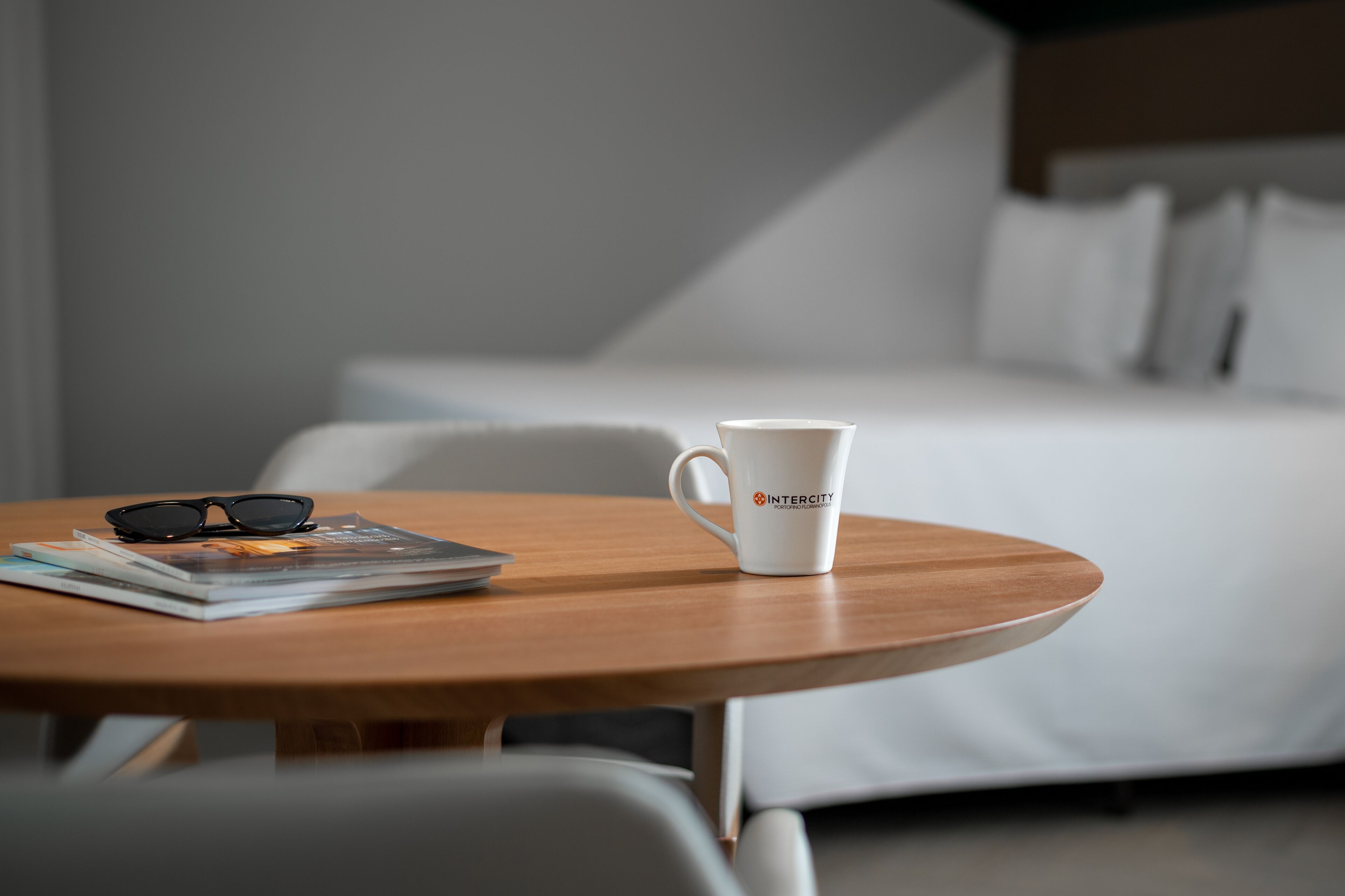A neatly arranged hotel room with a wooden table, a white mug, and a pair of glasses.