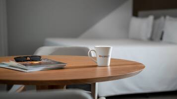 A neatly arranged hotel room with a wooden table, a white mug, and a pair of glasses.