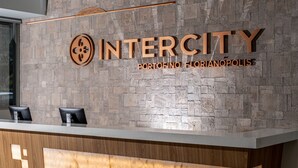 Una recepción con fondo de pared de piedra, un logotipo y el texto "INTERCITY PORTOFINO FLORIANOPOLIS".