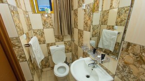 A bathroom with a toilet, sink, and mirror. - Zebra Tourism  Hotel (Kigali)