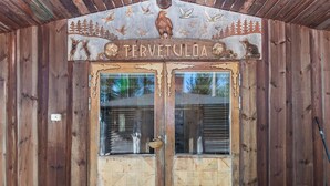 Eingang eines Holzhauses mit einem Schild, auf dem 'TERVETULDA' steht.