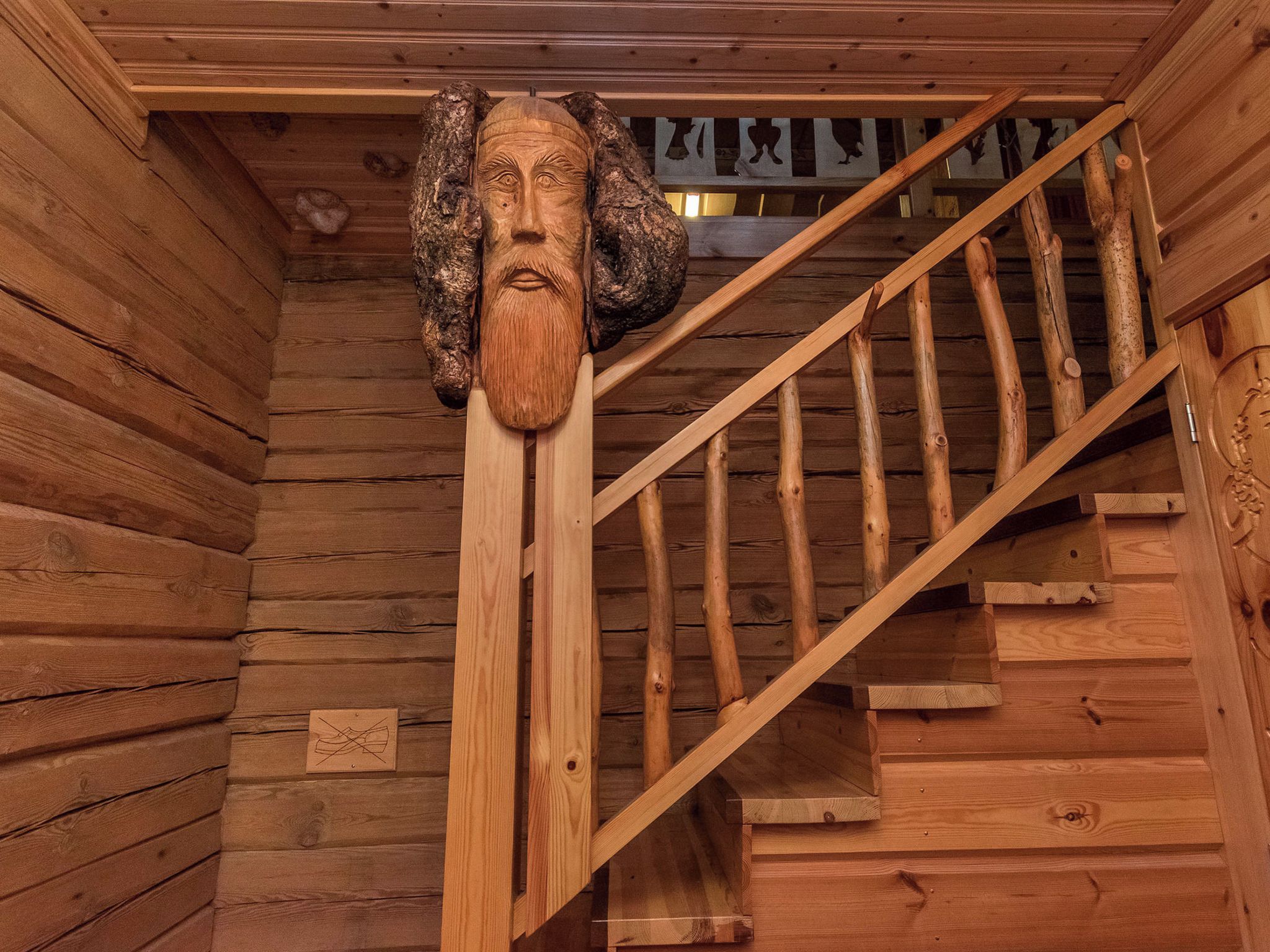 Eine Holztreppe mit einem geschnitzten Holzkopf oben.