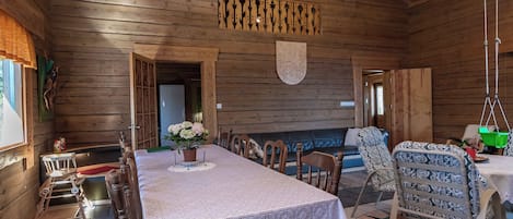 A wooden interior with a dining table, chairs, and a hanging light fixture.