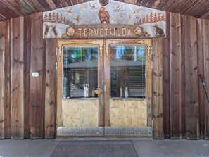 Une porte en bois sur laquelle est gravé le mot « TERVETULIA », encadrée de sculptures représentant des animaux et des arbres.
