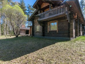 A wooden cabin with a balcony, surrounded by trees and a grassy yard. - Villa kesäranta by Interhome (Kesälahti)