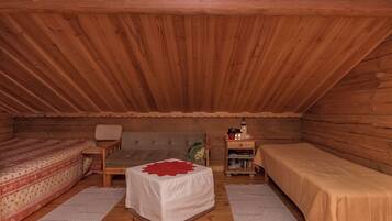Ein gemütliches Schlafzimmer im Dachgeschoss mit zwei Einzelbetten, einem kleinen Tisch und einem Stuhl.