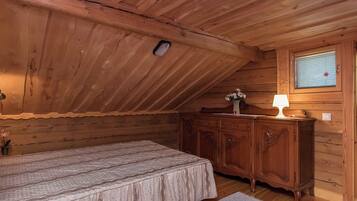 Quarto de madeira com cama, cômoda e janela com persianas.