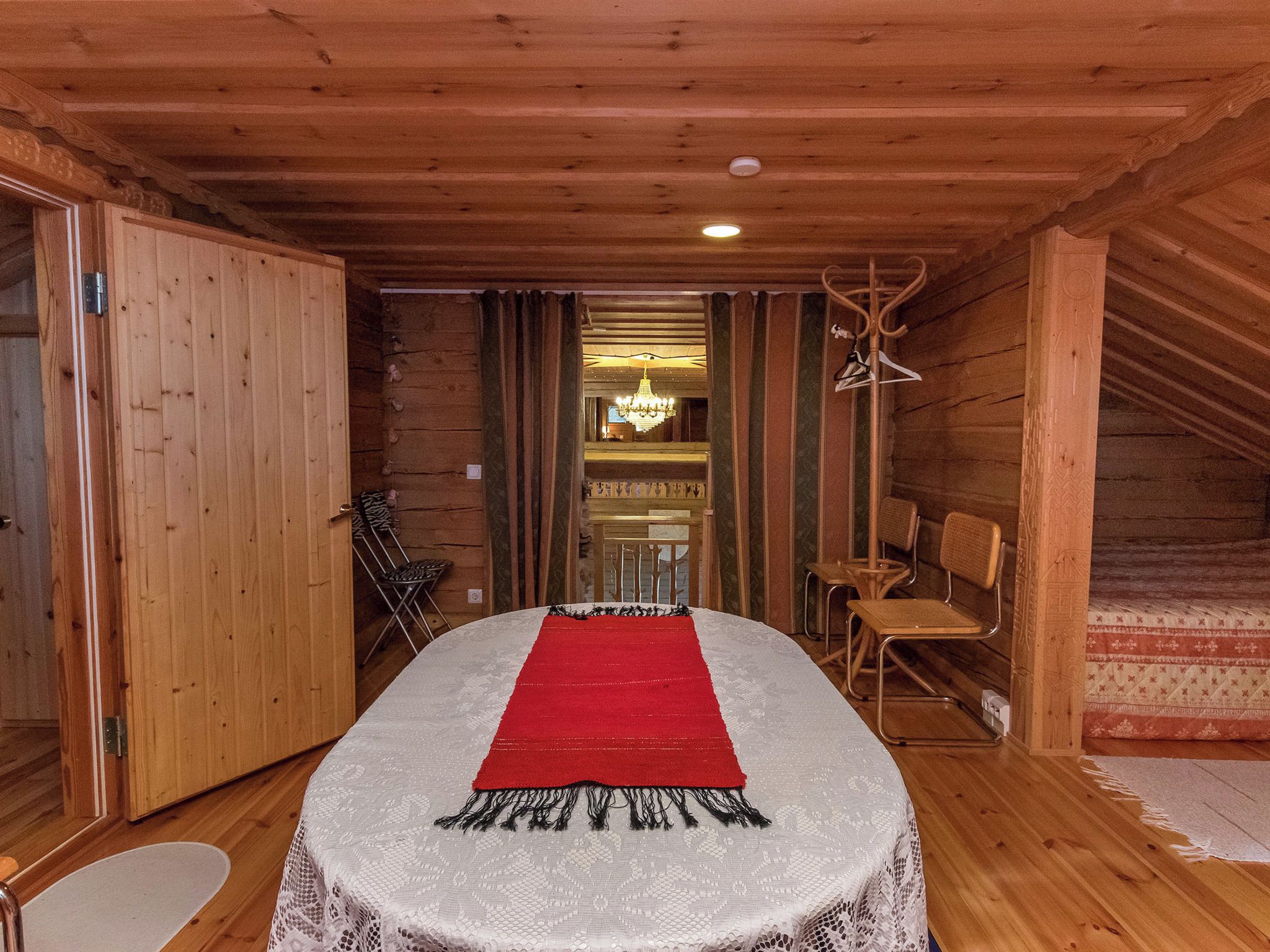 Un intérieur en bois avec une table à manger, des chaises et un chemin de table rouge.