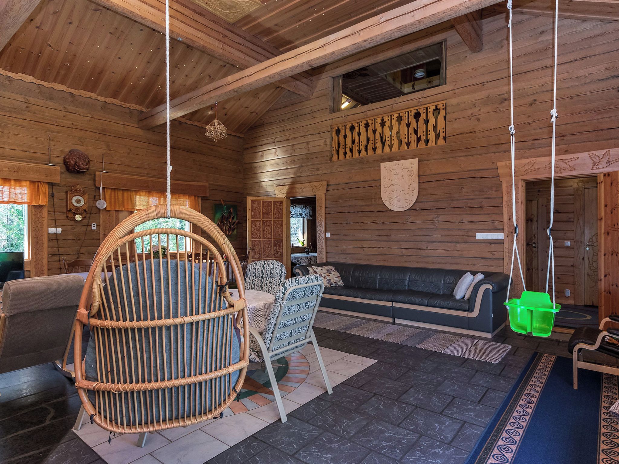A wooden interior with a rattan chair, a sofa, and a hanging basket.