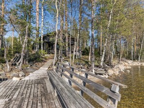 A wooden deck leading to a rustic cabin surrounded by trees.