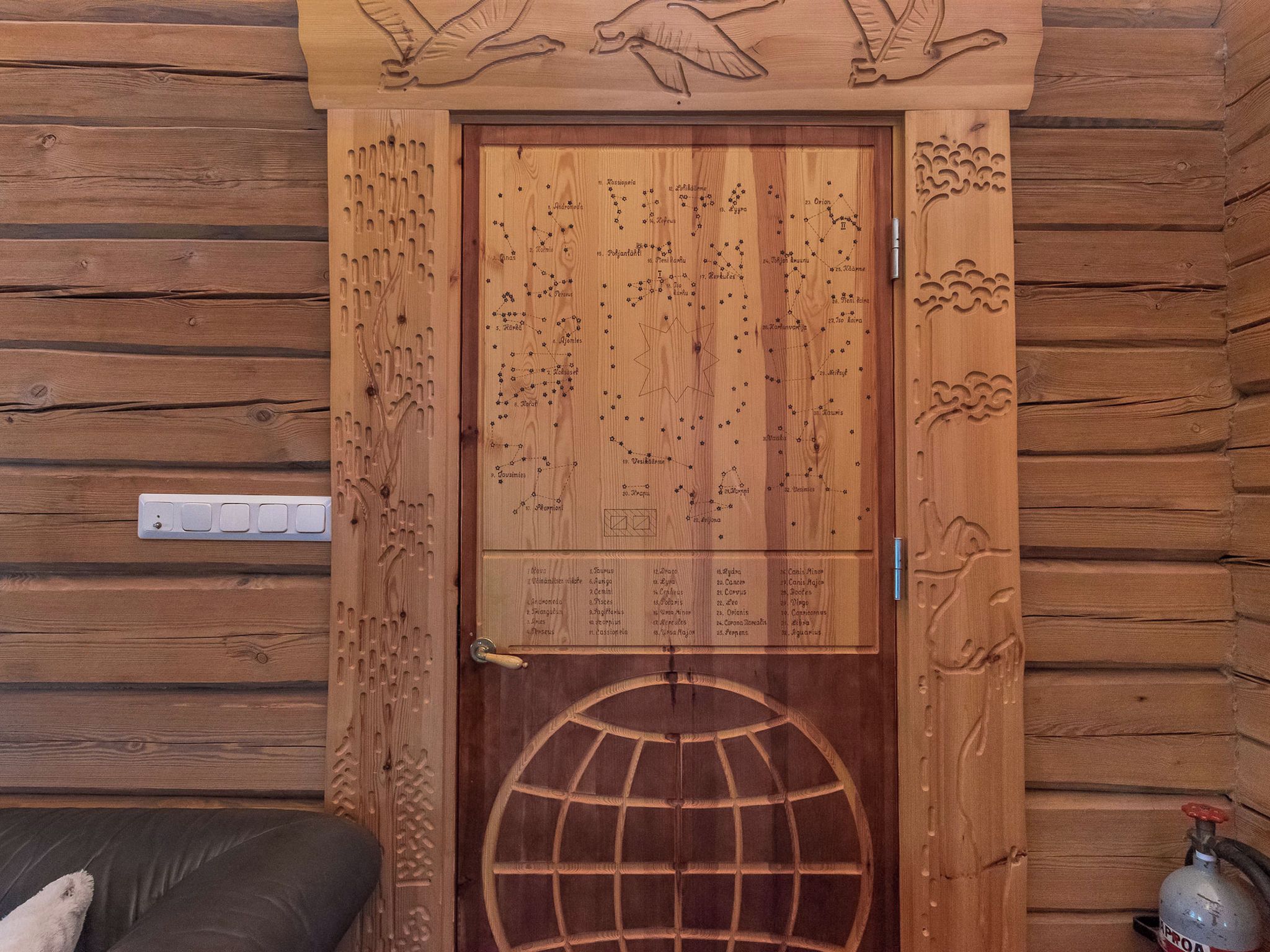 Una porta in legno con costellazioni intagliate e un motivo a globo.
