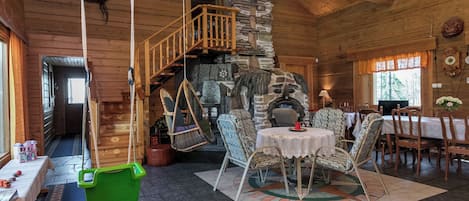 Ein rustikales Interieur mit Kamin aus Stein, Holzmöbeln und einer hängenden Schaukel.