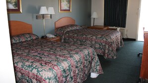Een hotelkamer met twee bedden, een bureau, een stoel, een lamp en een raam met gordijnen.
