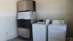 Een wasruimte met twee wasmachines en een gestapelde droger.