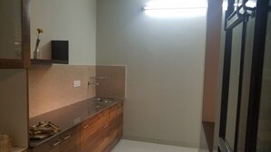 Una cocina pequeña y moderna con un lavamanos, armarios de madera y un florero sobre la encimera.
