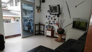 A living room with a black sofa, a small wooden table, a television mounted on the wall, and a potted plant. - Hotel Central - Mocoa (Mocoa)