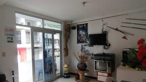 A room with a sliding glass door leading outside, a television mounted on the wall, a small table with a vase of flowers, and a dining table with chairs. - Hotel Central - Mocoa (Mocoa)