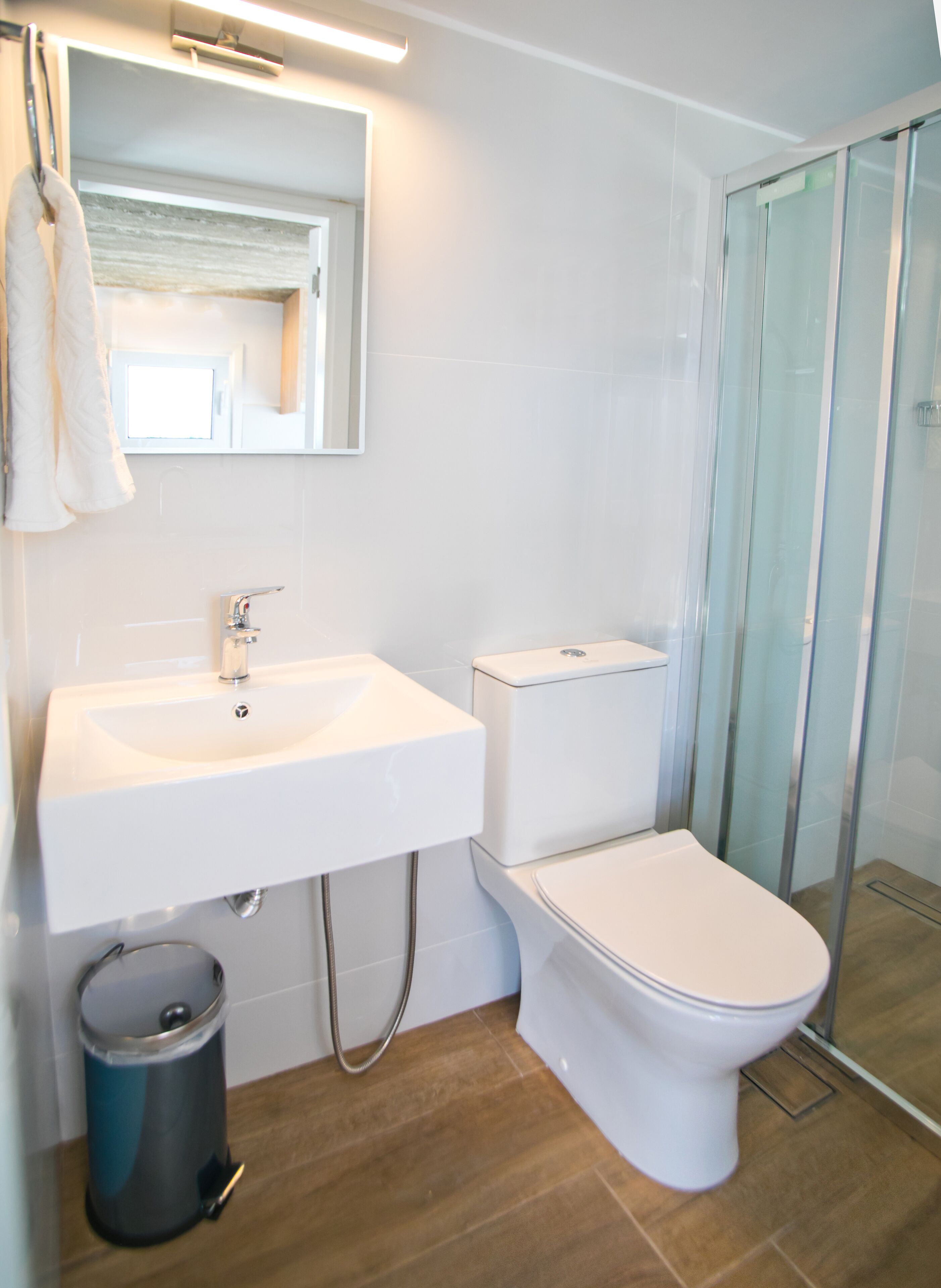Une salle de bain avec un lavabo blanc, des toilettes et une cabine de douche en verre.