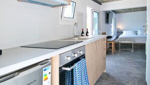 Eine kleine Küche mit Einbauofen, Kühlschrank und Holzschränken.