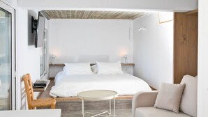 Ein modernes Schlafzimmer mit einem Bett, einem runden Tisch, einem Holzstuhl und einer Couch.