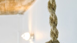 Ein Detailaufnahme eines Seils, das um einen zylindrischen Gegenstand gebunden ist, vermutlich ein Dekorationselement im Raum.