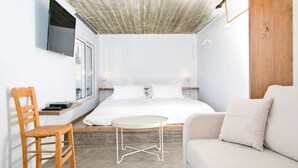 Ein modernes Schlafzimmer mit einem Bett, einem Holzstuhl, einem kleinen runden Tisch und einer Couch.