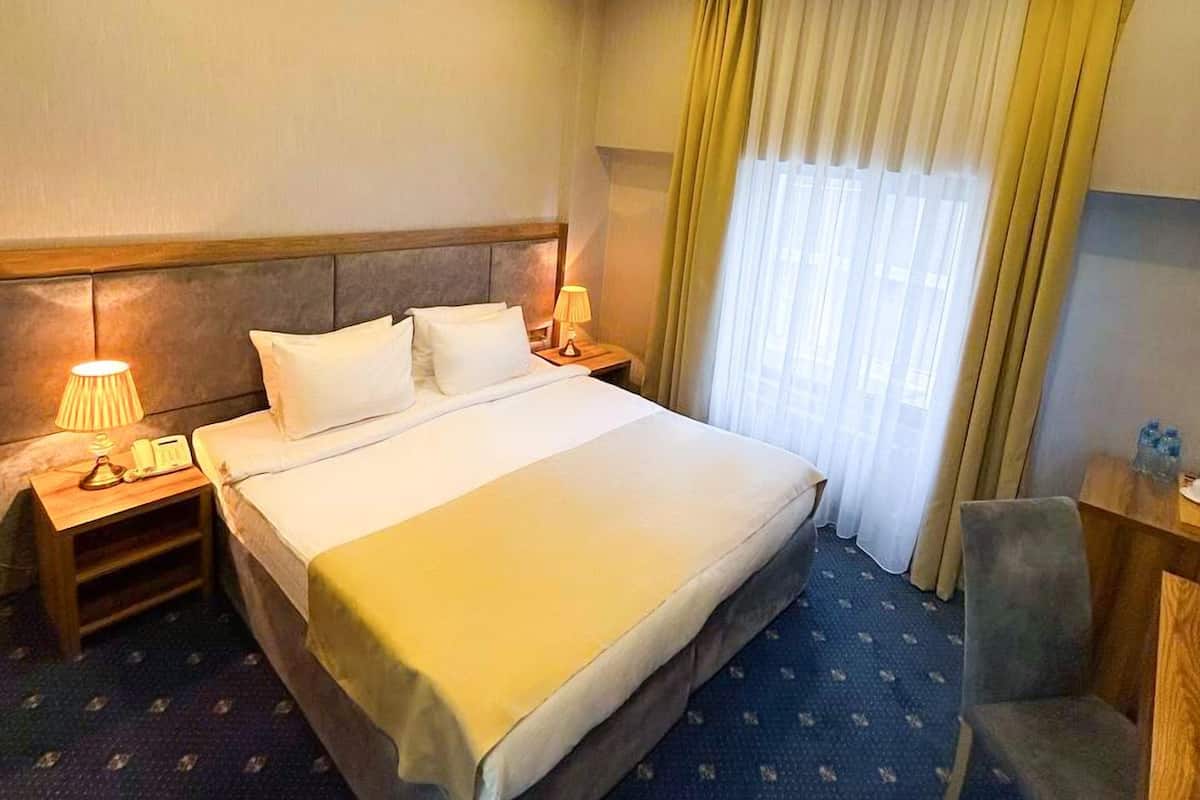 Une chambre d’hôtel avec un grand lit, des tables de chevet avec des lampes, une chaise et un bureau.