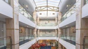 A multi-level atrium with glass railings, marble walls, and a central open space with a ceiling structure. - Grand Midway Hotel (Baku)